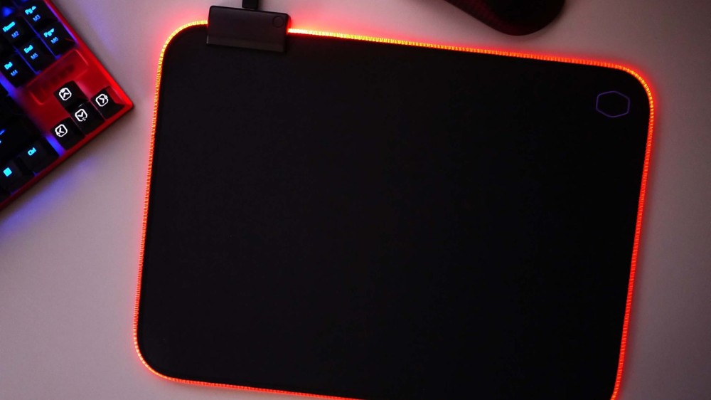 An RGB mousepad with red and yellow lighting next to a keyboard.