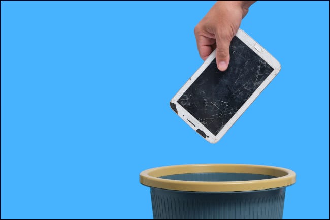 Broken Android tablet being dropped in a trash can.