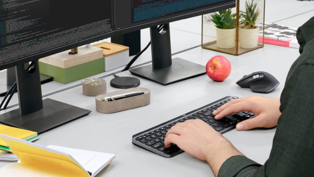 Person sitting at work desk typing on black wireless keyboard