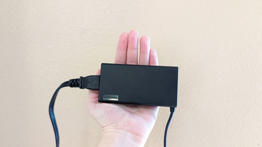 The Lenovo Slim 7i Pro X laptop's included AC adapter in a hand.